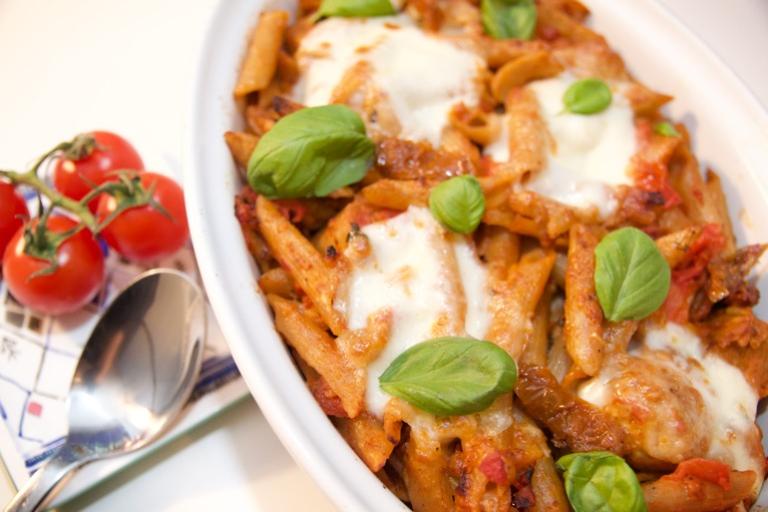 Plato de pasta con salchichas vegetarianas y cubierto con queso mozzarella y albahaca